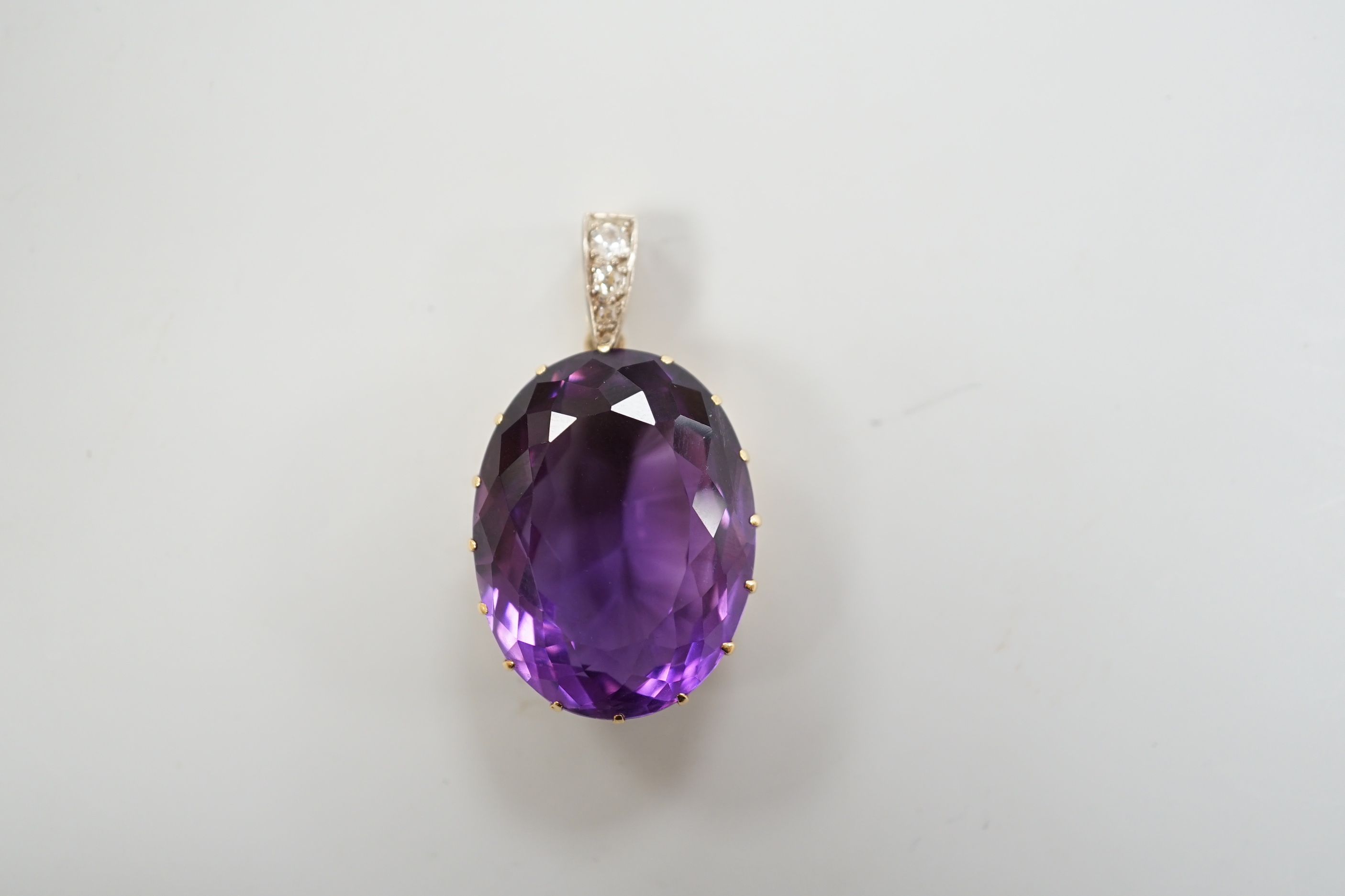 An Edwardian yellow metal, oval cut amethyst and three stone diamond set drop pendant, overall 4cm, gross weight 16.7 grams.